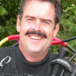 Tim Green in scuba suit in front of a tree